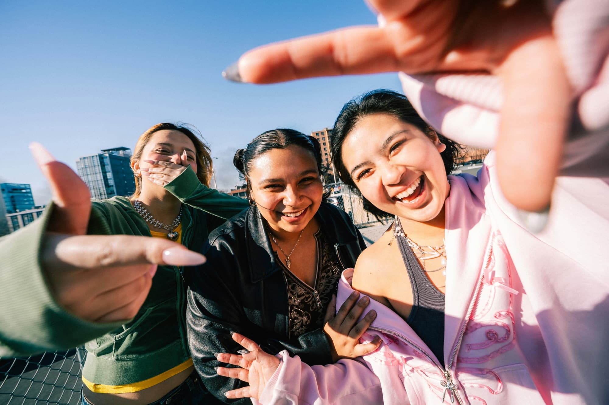 Three teens laughing together on a rooftop